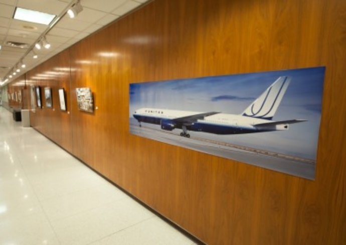 A large horizontal photo of a Unitied Airlines jet on a gallery wall at Brigham Young University. 