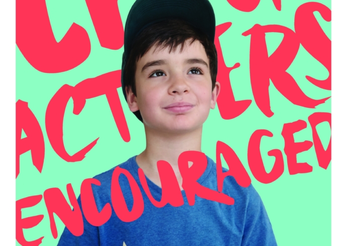 A close up of young boy in a cap on a green background with red, hand-painted text that reads, Characters encouraged.