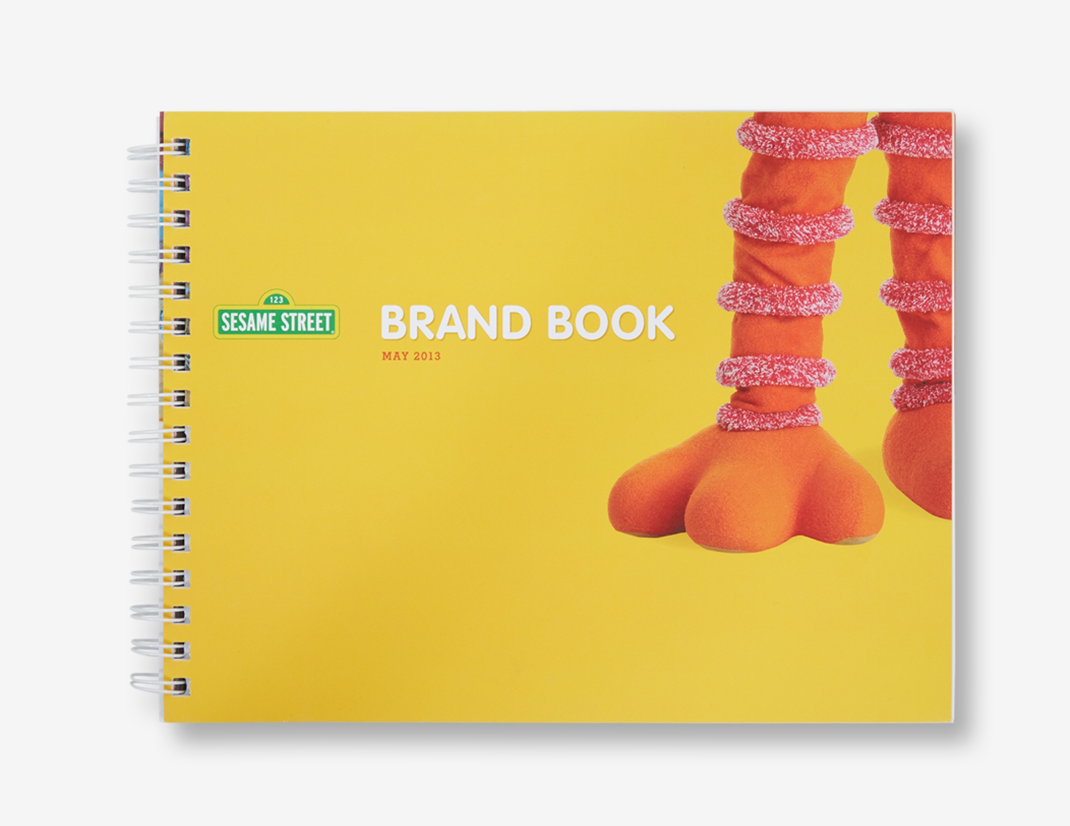 The cover of the Sesame Workshop Brand Book with a close up of the character Bird Bird's legs on a yellow background.