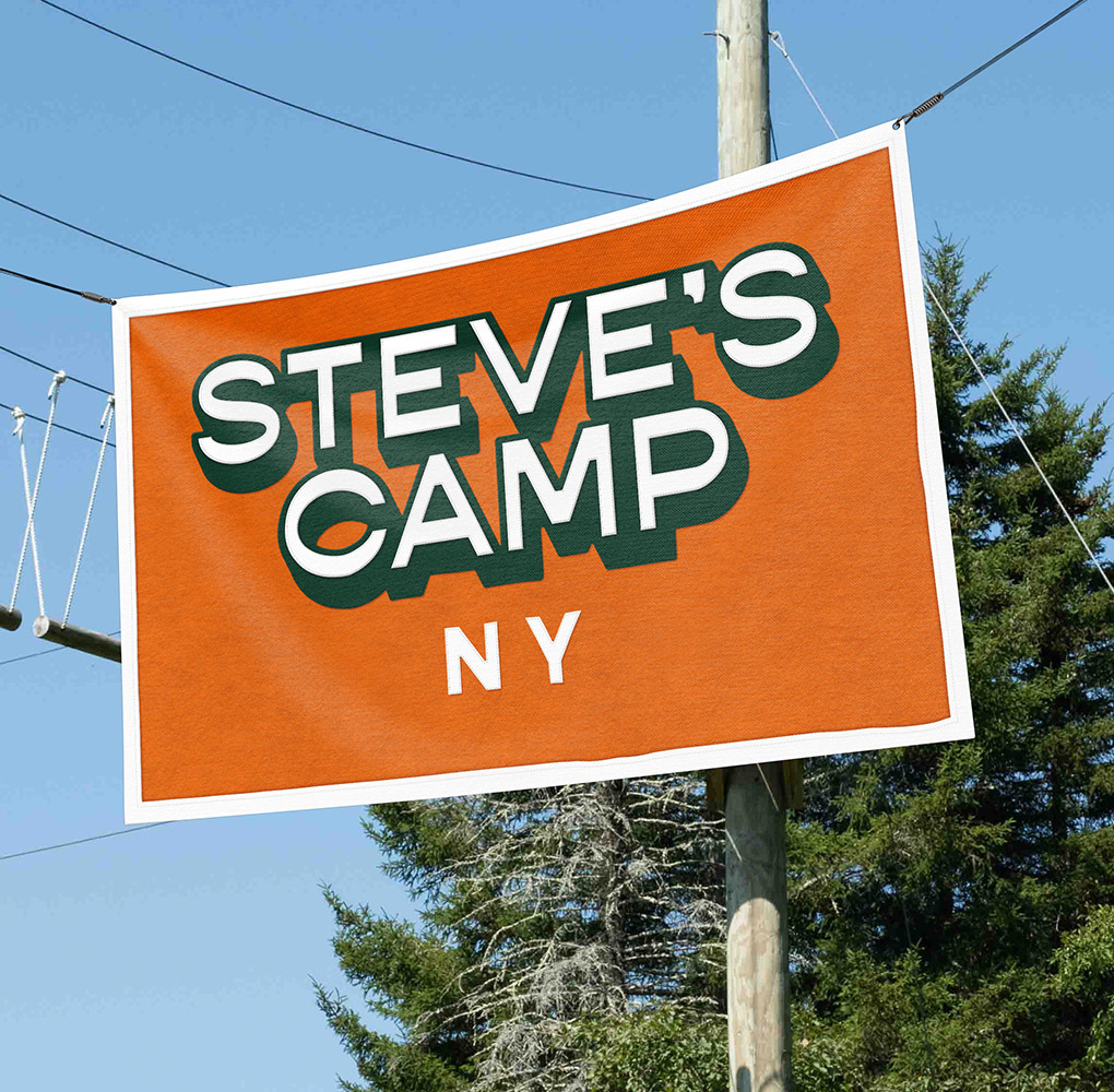 An orange flag with the camp logo against a backdrop of blue sky and trees