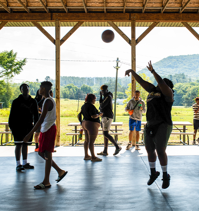 A group of campers playing basketball on a covered outdoor court