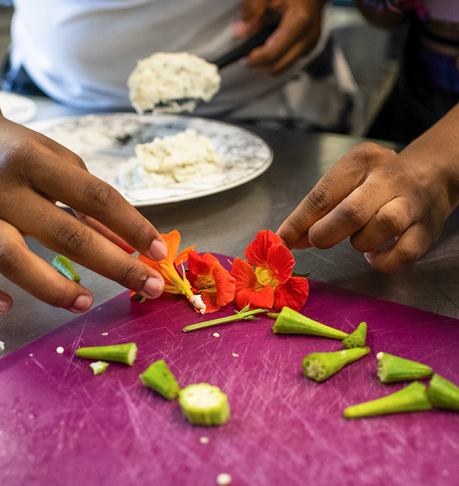 A close up of hands arranging flowers as part of a meal