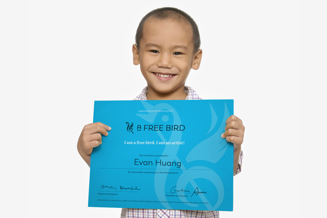 A young child holding a certificate from the arts organization A Free Bird, with the text, I am a free bird; I am an artist.