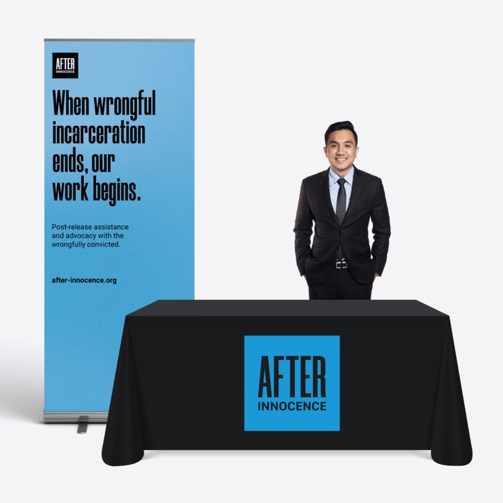 An After Innocence team member stands behind a table at an industry conference with a table covering and tall banner displaying the organization's logo and slogan: when wrongful imprisonment ends, our work begins.