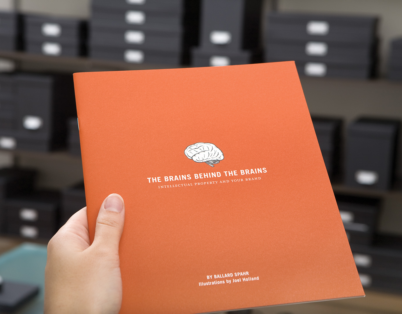 An orange Ballard Spahr brochure with an illustration of a disembodied brain, and the title, The brains behind the brains.