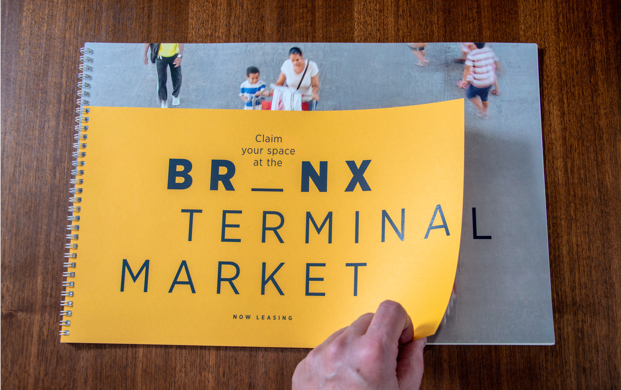 A hand pulling open the cover of the Bronx Terminal Market leasing brochure.