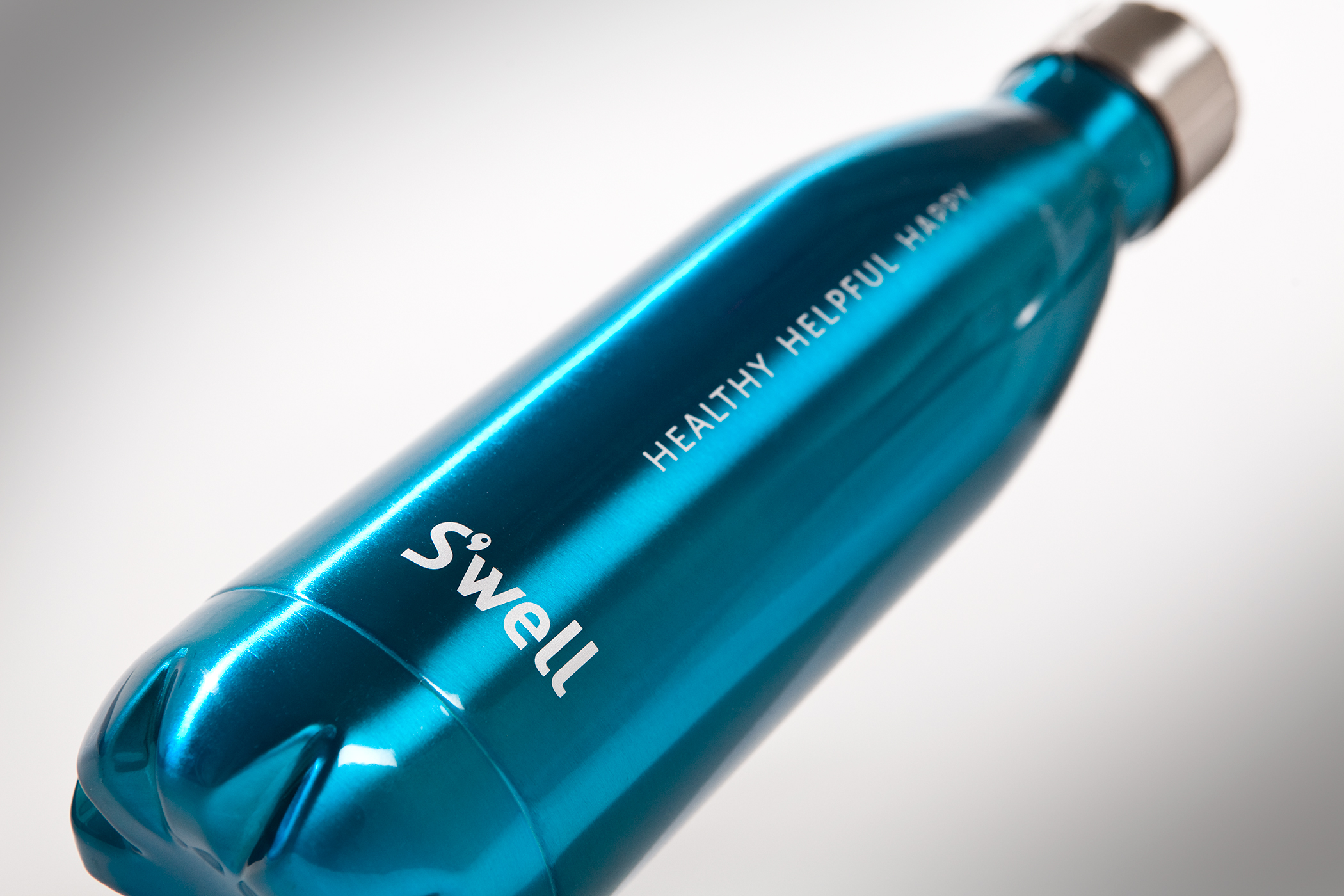 A blue metallic water bottle imprinted with the Swell logo and the phrase "Healthy, helpful, happy."