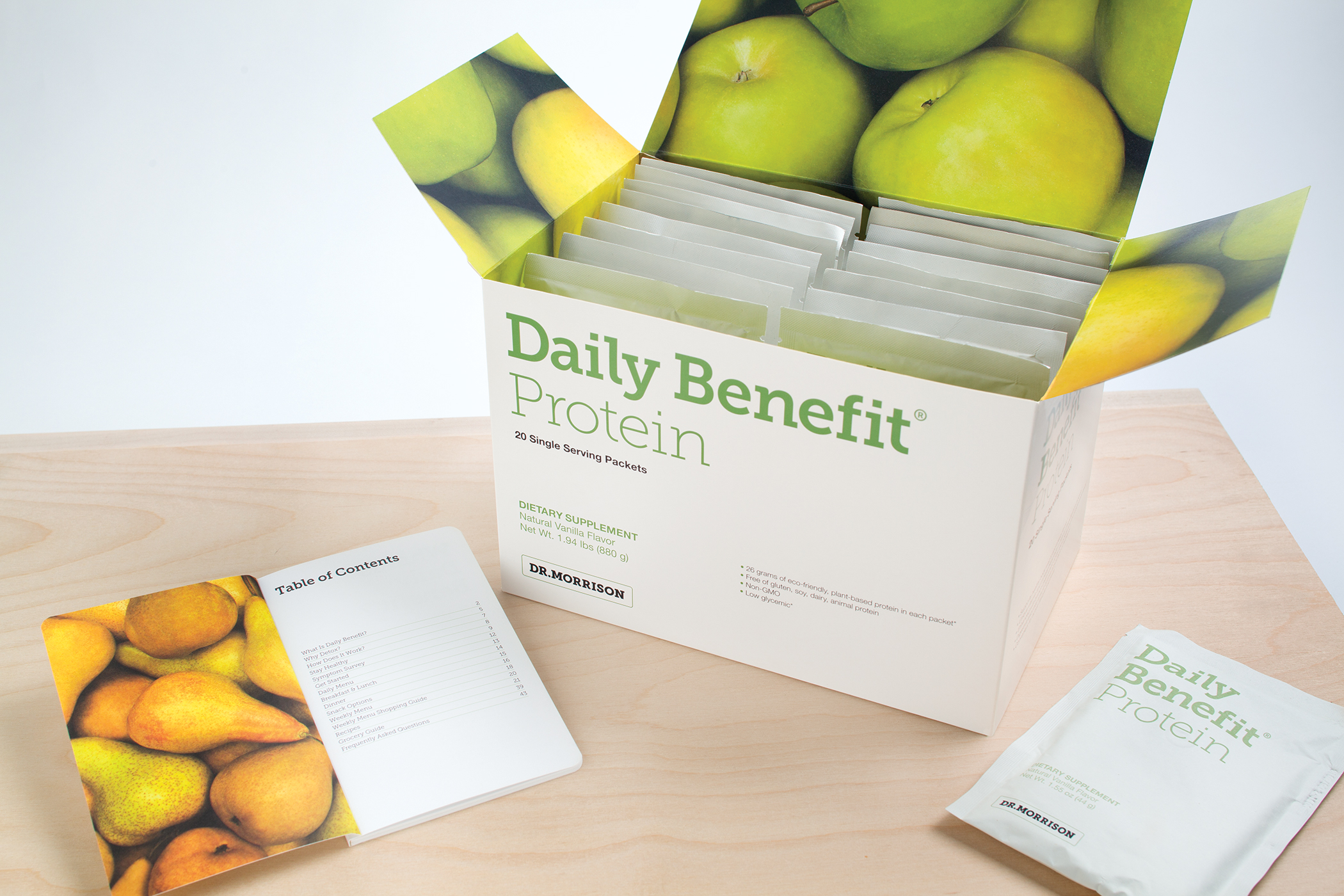 An opened Dr. Morrison Daily Benefit protein packaging box with images of green apples on the lid and flaps.