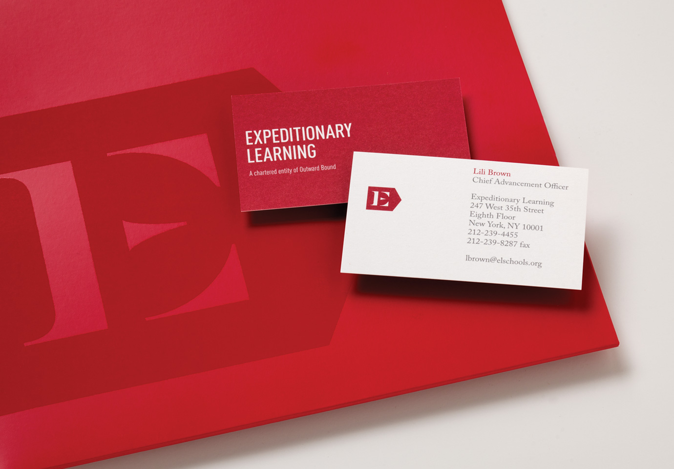 An crimson-branded Expeditionary Learning folder and business cards with the company logo.