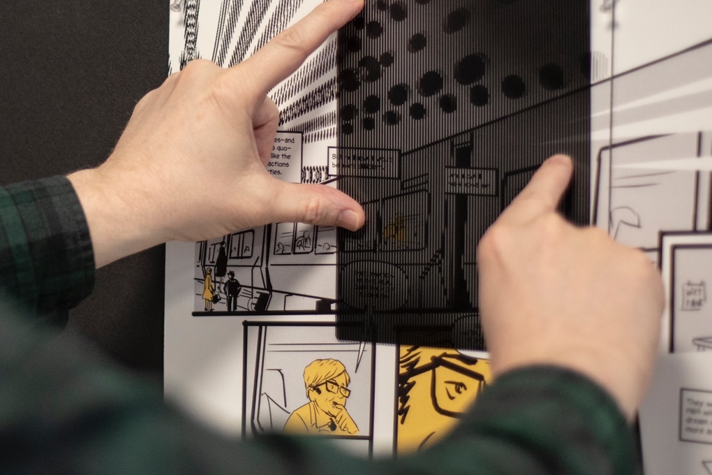 Two hands move a filter over a page of Instinet's Fintech at Fifty graphic novel to view the special animated illustrations.