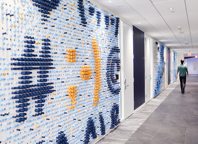 A wall sculpture in the KCG office made of hundreds of colored wooden dowels depicting a hashtag and typographic symbols. 