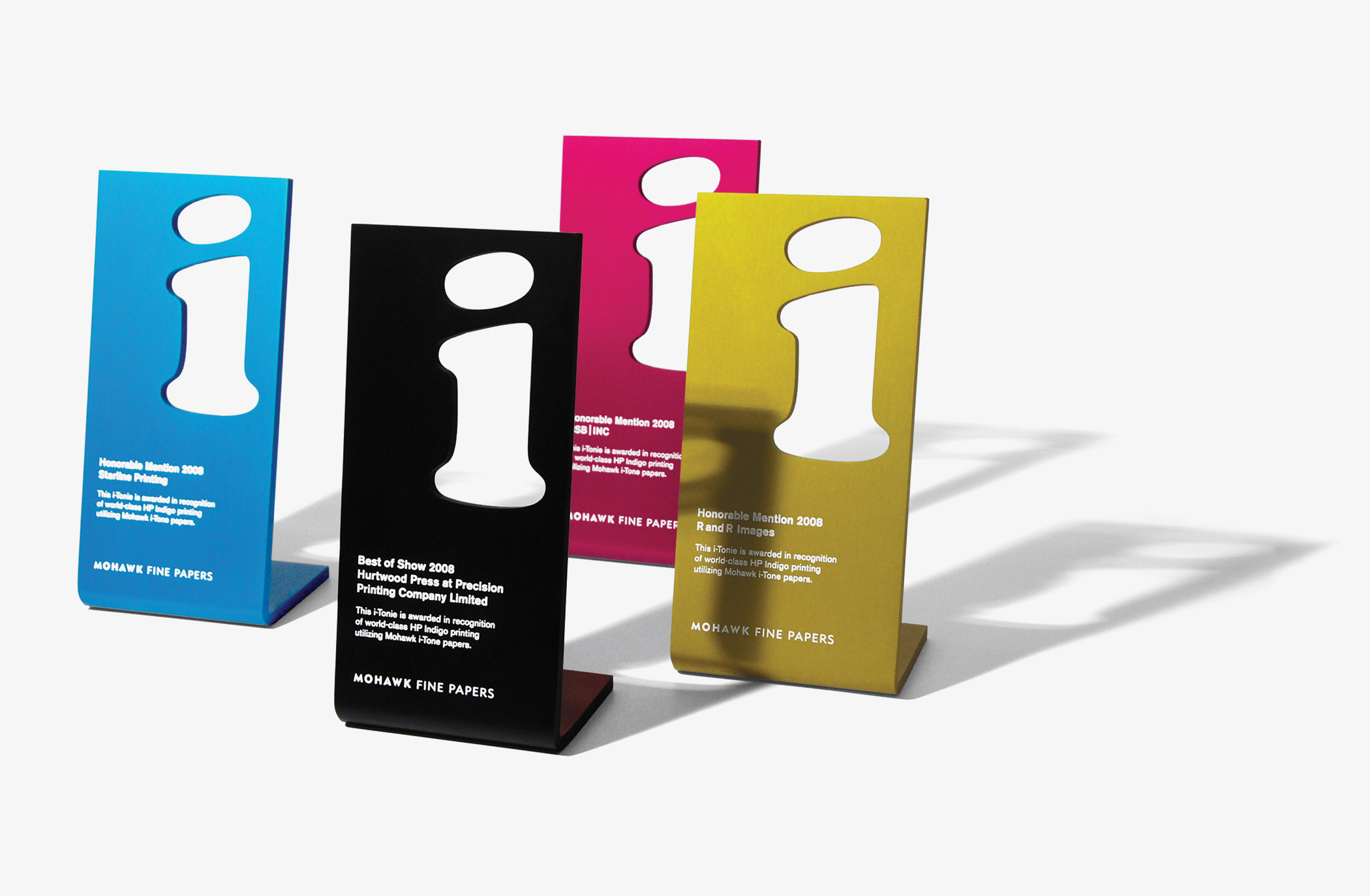 A set of four colorful Mohawk Fine Papers I tonies award statuettes with a cut-out lowercase letter I.