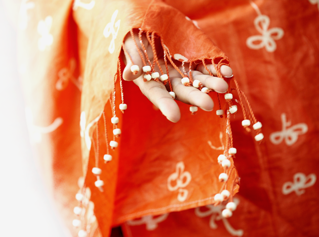 An example of Think Responsive brand photography: a open hand in the sleeve of an orange patterned fringe garment.